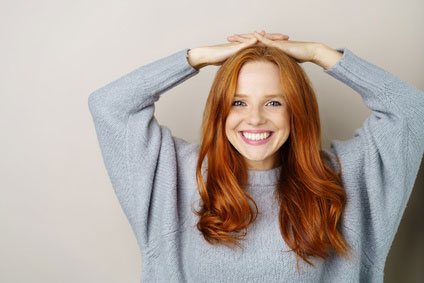 Rothaarige Frau mit grauem Pullover aus Strick-Stoff Rothaarige Frau mit grauem Pullover aus Strick-Stoff