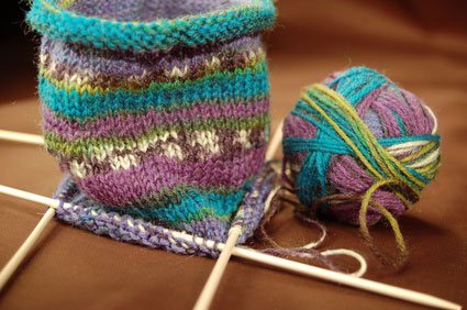 Bunte Sockenwolle mit begonnenem Socken auf Stricknadeln 